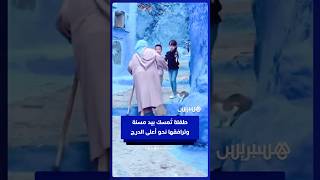 مشهد دافئ لطفلة تسند مسنة وهي تصعد الدرج بشفشاون thumbnail
