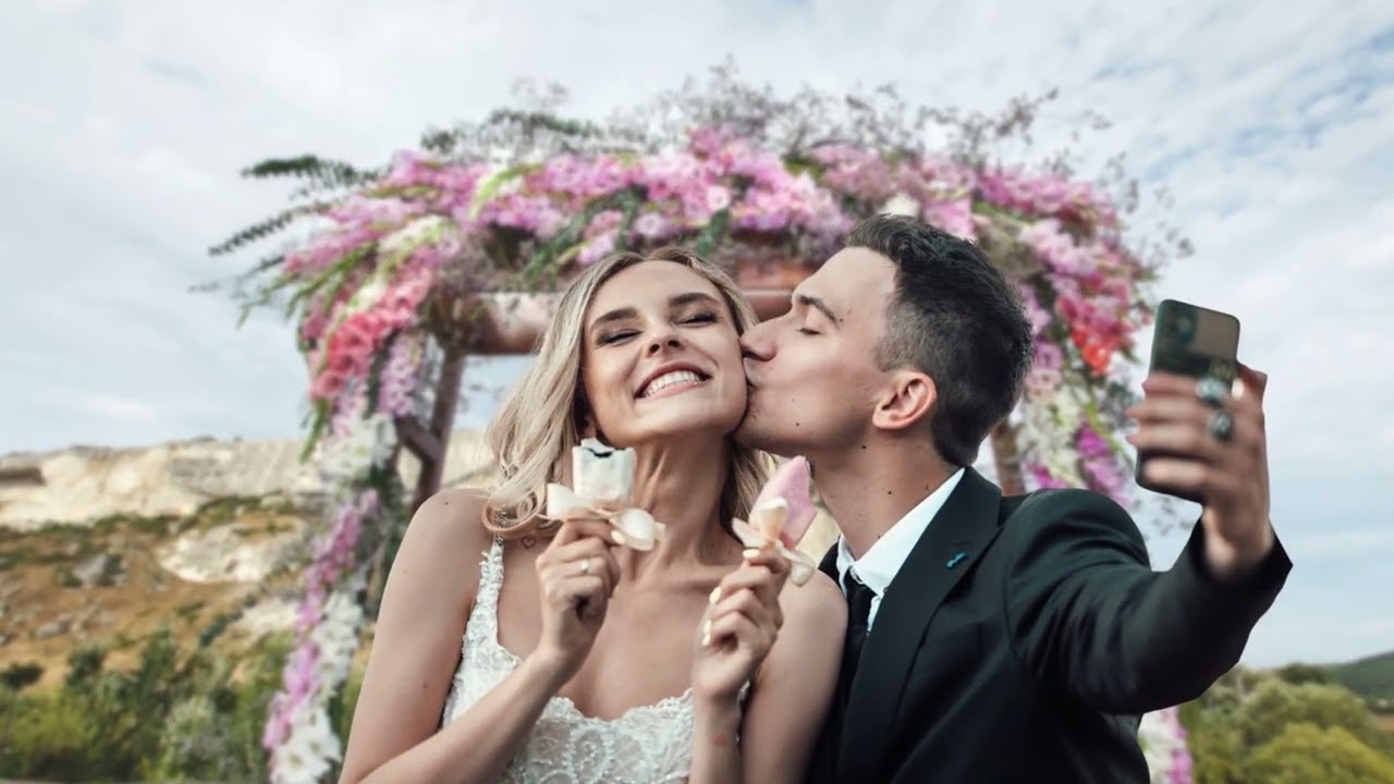 Couple kissing by floral arch, enjoying flower-shaped desserts. Flower delivery Hollywood.