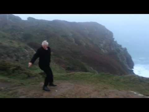 Man trying to stand up in high winds on cliffs at Grosnez point on Jersey Channel Islands UK