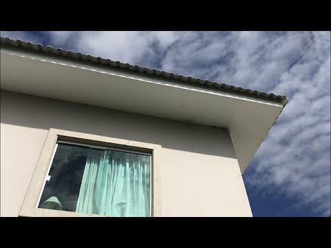 Tirando as teias de aranha no beiral do telhado da casa