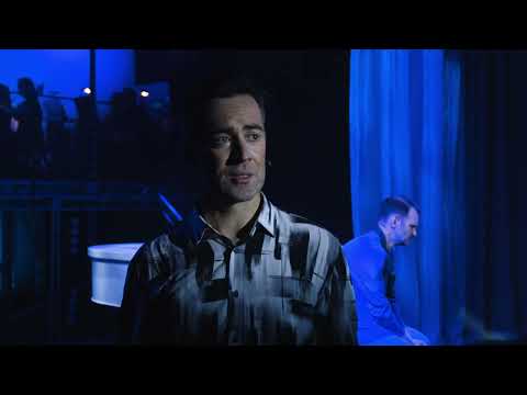 The Boy from Oz trailer-style promo image with spotlighted performer at a piano and chorus line