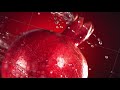 Super slow motion water drips on rotating pomegranate . On a black background.