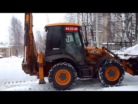 Трактор JCB убирает снег у садика.