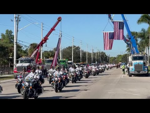Tow truck drivers line streets with US flags to honor fallen deputies