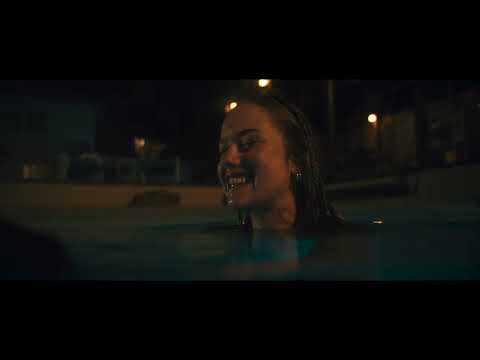 Night Swim official trailer frame: backyard pool at dusk with eerie blue light rippling toward camera