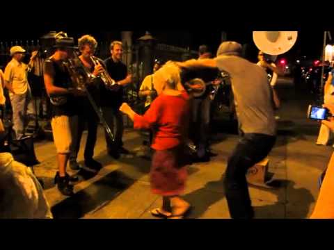New Orleans street scene where young man passing by dances with old woman