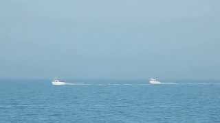 Fishing boats speed and play off Prestatyn Beach Denbighshire Wales UK