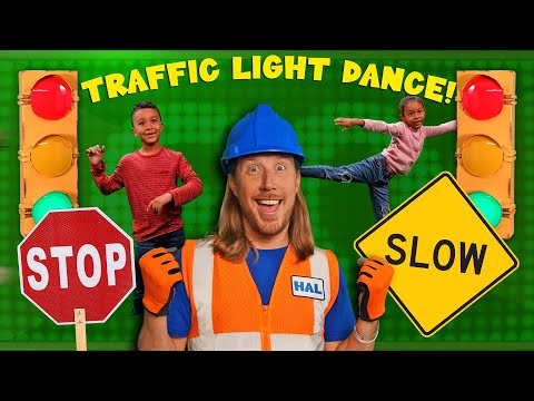Bright kids’ video thumbnail with a smiling man in a hard hat and safety vest, STOP and SLOW signs, traffic lights, and a green background; “Traffic Light Dance” implied.