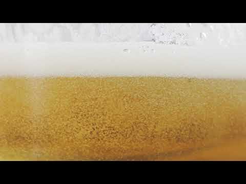 FREE STOCK VIDEO 4K | Detail Shot of Rippling Beer Bubbles and Foam in Glass