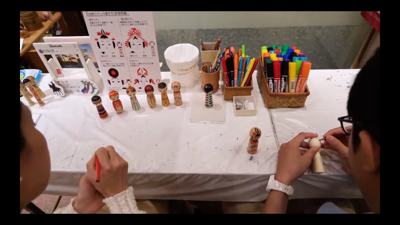 Travelers delight in the art of painting miniature Kokeshi dolls.