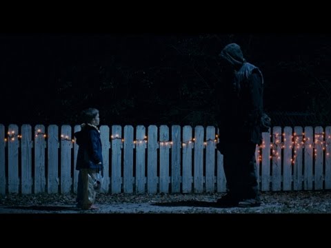 Trailer still: Laurie Strode in shock-lit close-up, audio crossfading between score and needle-drop