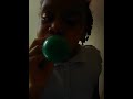Girl Blowing A Green Balloon To Pop