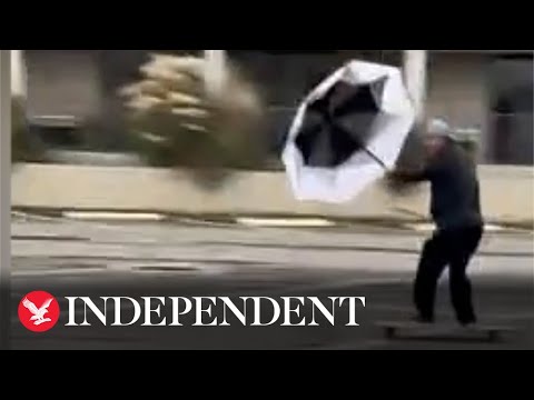 Skateboarder uses umbrella as sail in Hurricane Ian winds
