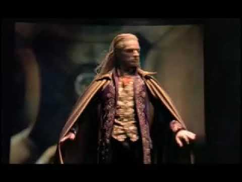 Trailer still of coven tableau with masks and footlights implying Morality Play sequence