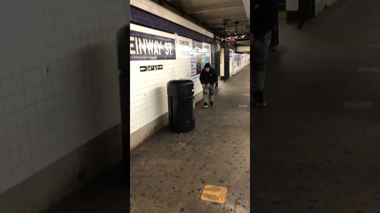 Guy tries to knock down a garbage bin in the subway