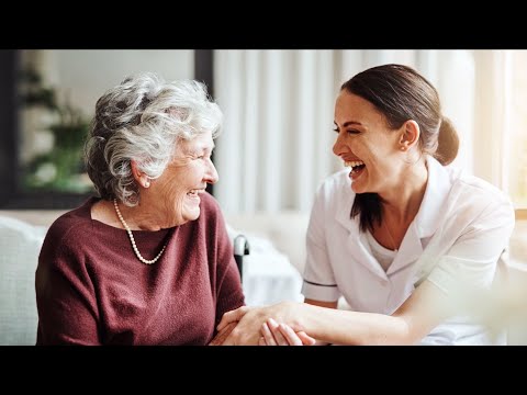 Senior woman in wheelchair enjoying time in the park with caregiver