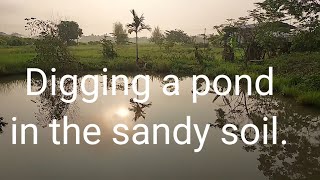 Digging a pond in the sandy soil.