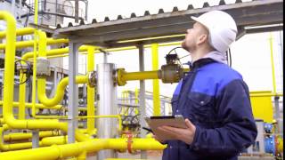 engineer holding a tablet, talking on walkie-talkie and smiling at camera in modern industrial