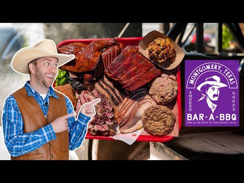 Man in a cowboy hat and blue plaid shirt points excitedly at a red tray of smoked meats (ribs, brisket, turkey) in a BBQ setup with a purple Bar-A-BBQ sign from Montgomery, Texas.