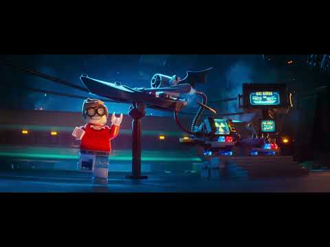 Main trailer frame: LEGO Batman dives toward Gotham’s power plant as guitars and drums punch