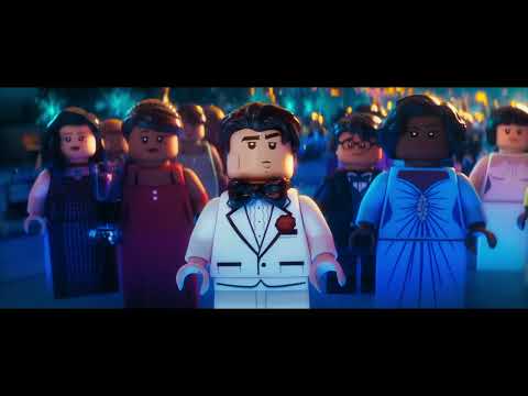 Trailer collage: Batmobile drift, gala chaos, Fortress of Solitude reveal; music toggles from riff to disco gag