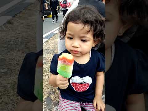 Hasna Alfa Fadila sedang makan ice cream pelangi