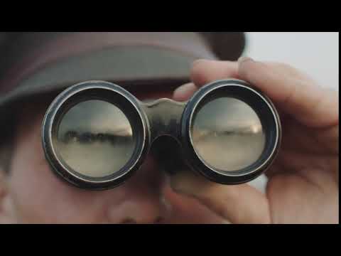 man looks at the terrain through binoculars mirror reflection of the lands