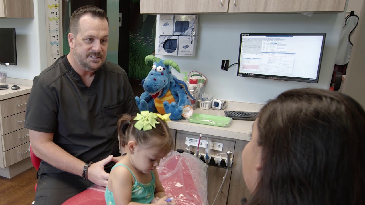 Garland pediatric dentist talking to mother of young girl in dental chair
