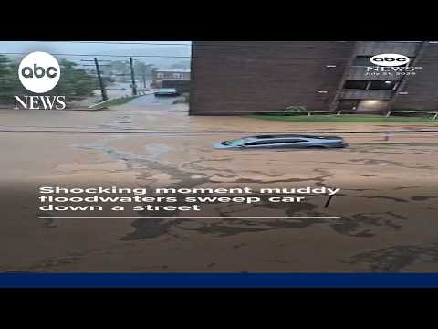 Shocking moment muddy floodwaters sweep car down street