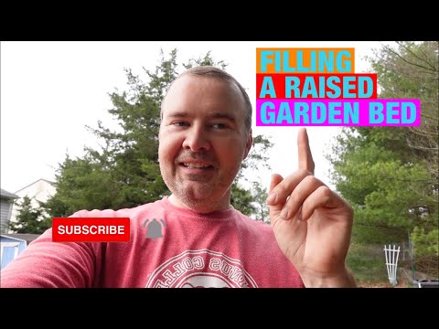 Filling a raised garden bed with a mix of compost, peat moss, and vermiculite.