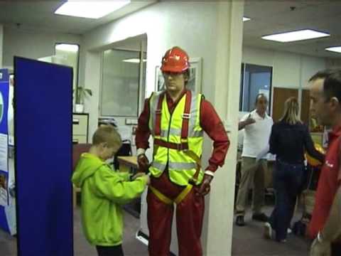 Safety harness competition joke with living mannequin #4 (flash) mannequin-man performming as a Living Mannequin: Fall arrest harness being put onto mannequin man by member of the public at a Safety clothing and PPE exhibition by ARCO at family open day at BAE (British Aerospace Engineering) systems in Rochester #4 (flash) for Arco on 06/07/2002