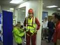Fall arrest harness being put onto mannequin man by member of the public at a Safety clothing and PPE exhibition by ARCO at family open day at BAE (British Aerospace Engineering) systems in Rochester #4 (flash) Fall arrest harness being put onto mannequin man by member of the public at a Safety clothing and PPE exhibition by ARCO at family open day at BAE (British Aerospace Engineering) systems in Rochester #4 (flash)