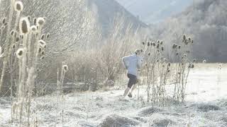 slow motion man trail running through frosted field