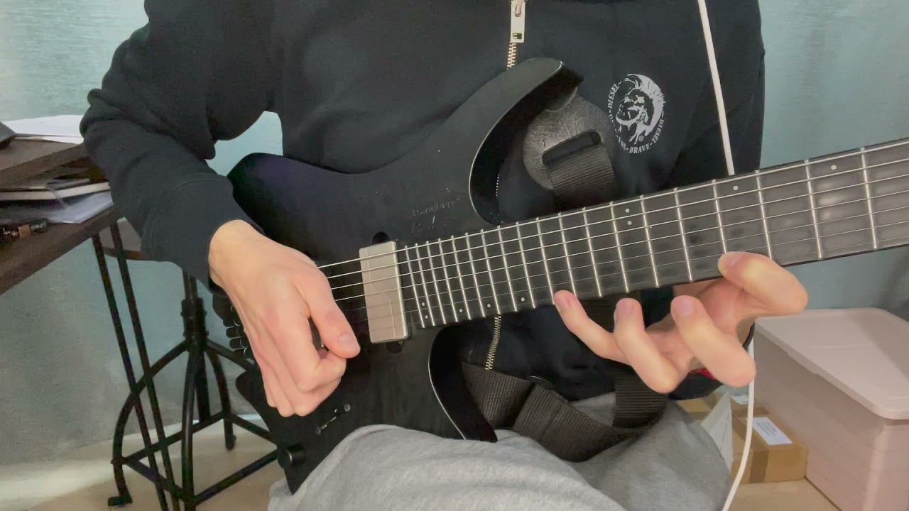 Close-up of a fretting hand spreading four fingers wide across a single guitar string