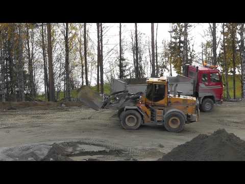 Ljungby l15 loading two buckets of gravel on a volvo fh12 for a road entrance