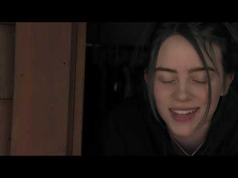 Apple TV+ trailer still for Billie Eilish: The World's A Little Blurry showing Billie onstage under blue light