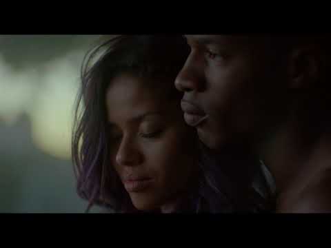 Trailer still: Noni under blue stage wash with microphone, crowd in silhouette