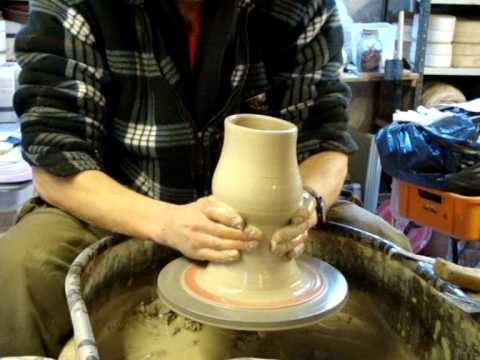 Throwing making a flared clay pottery vase on the wheel
