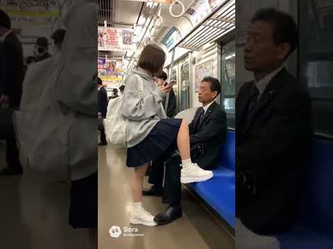 日本の満員電車の風景　主役は今風の女子学生　女子学生は片足を座席の上にのせており、それを隣の人が注意する