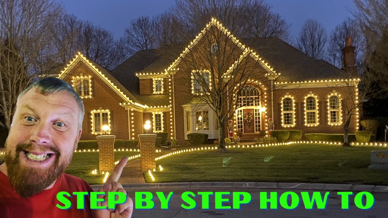 Professional Christmas light color combinations on a home with warm white rooflines and red wreath accents