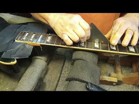 Checking with a rocker to find high spots on the frets.
