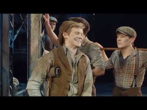 Newsies carrying the banner