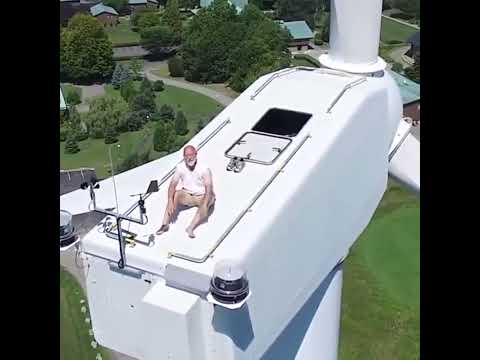 Drone captures a man sunbathing on a wind turbine