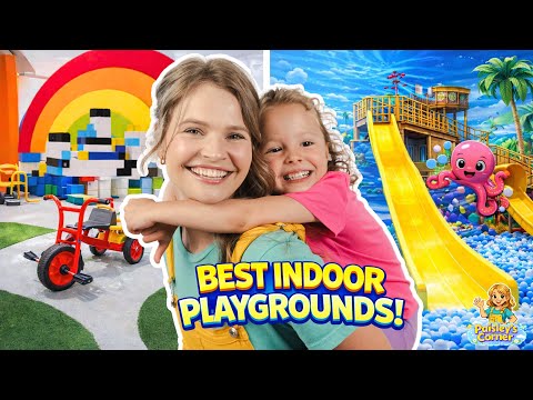 Smiling woman hugs a cheerful girl in a colorful indoor playground with a rainbow, blocks, tricycle and yellow slide in the background.