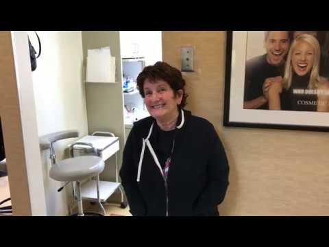 Woman in black jacket smiling outside of dental treatment room
