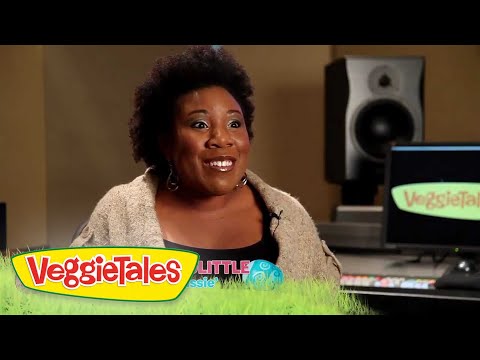 Smiling woman being interviewed in a recording studio, with VeggieTales branding visible on the monitor and a colorful footer graphic.