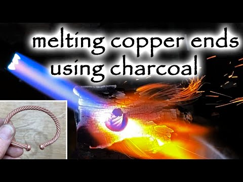 Using charcoal when melting copper ends of a cuff bracelet.