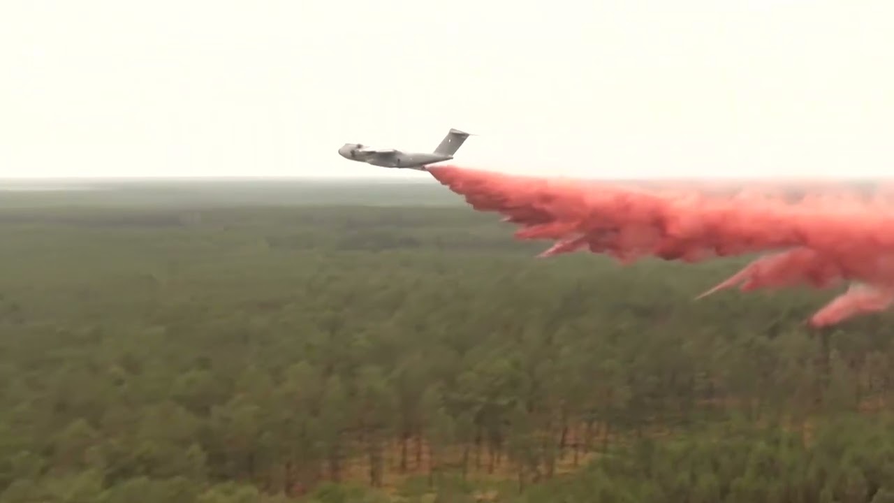 French military aircraft deploys fire retardant over forest wildfire