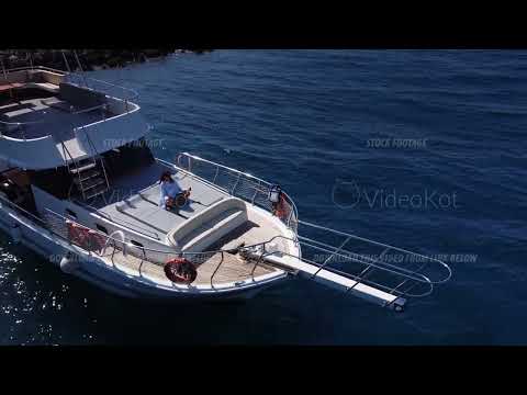 Caucasian woman is doing yoga sitting in lotus position on the deck of motorboat in blue sea