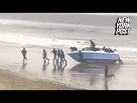 VIDEO: Dozens of migrants rush past shocked CA beachgoers after speedboat suddenly washes ashore